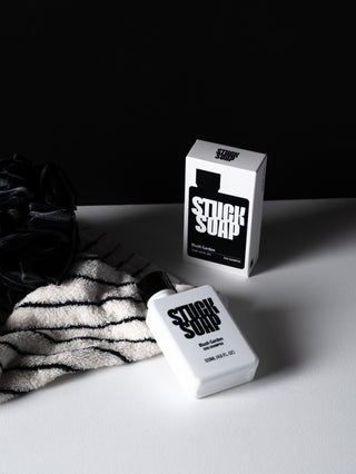 White Blush Garden 120 ml bottle lying beside its carton, with a striped towel and a black loofah