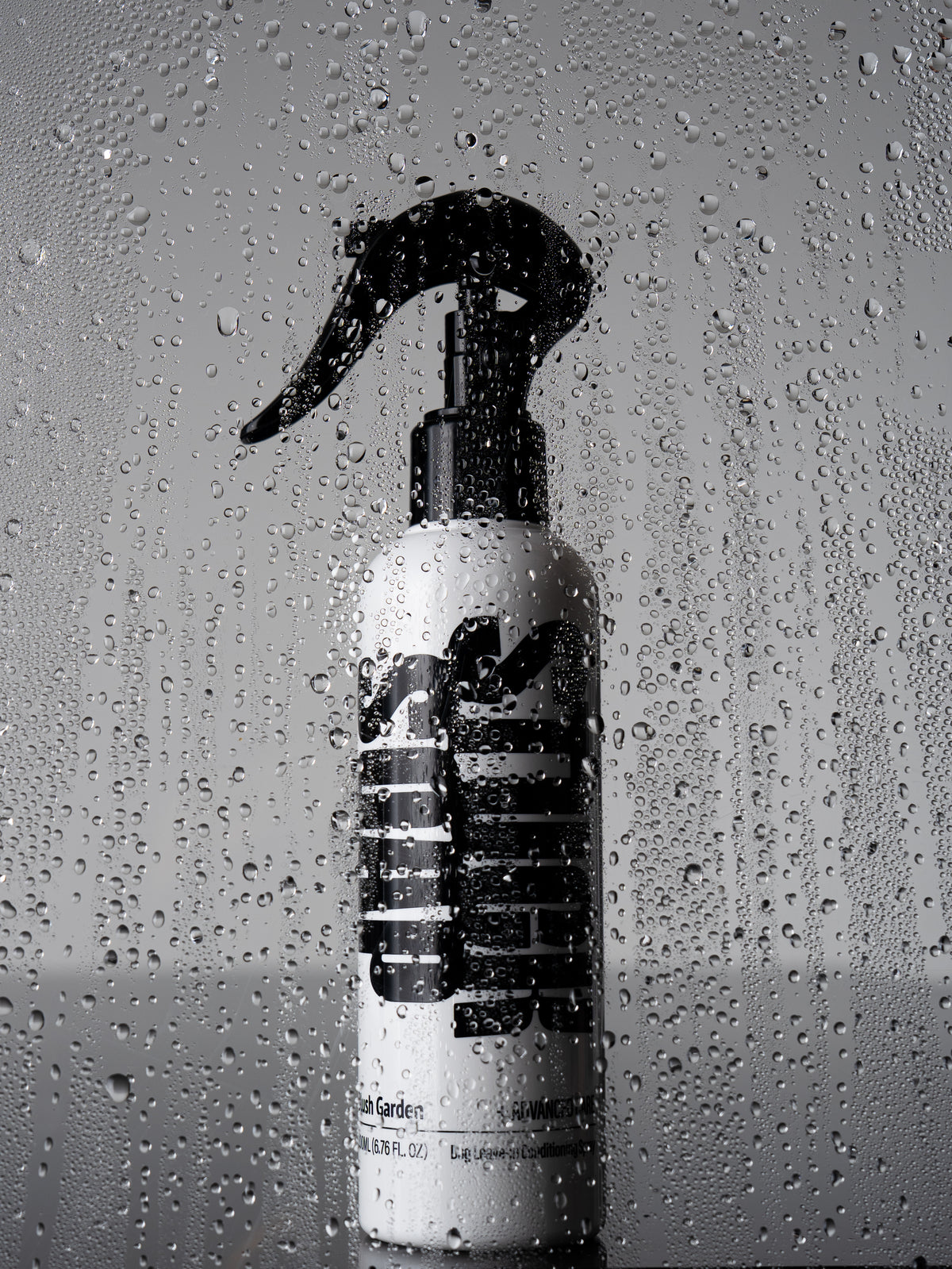 White Blush Garden leave-in conditioning spray bottle behind a pane covered in water droplets