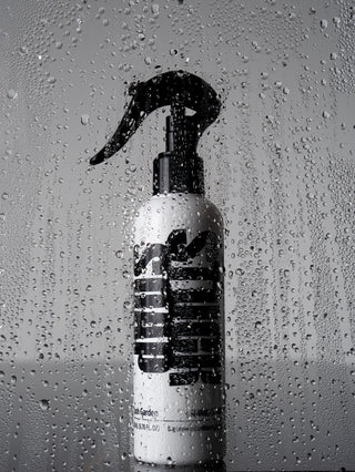 White Blush Garden leave-in conditioning spray bottle behind a pane covered in water droplets